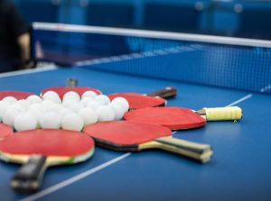 Group of Table Tennis Balls and red Bats on a blue table tennis table